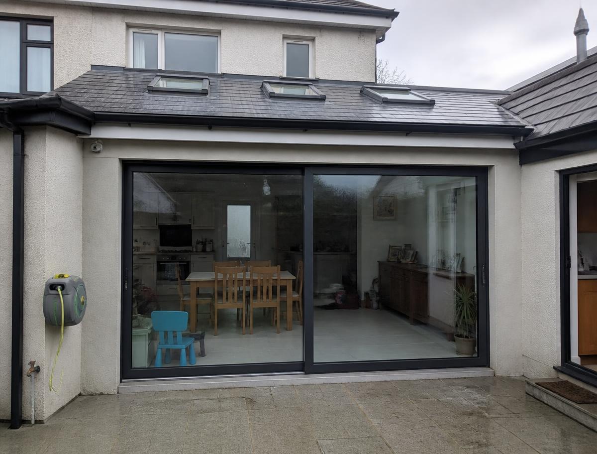 Rear house extension with glazed sliding doors at dusk